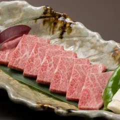 Wołowina wagyu a kobe: czym dokładnie różnią się te gatunki? Delikatne plastry marmurkowego mięsa na liściu, z pieprzem i grzybami.