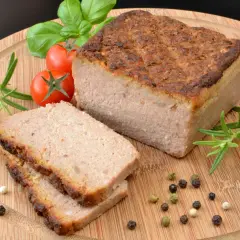 Upieczony pasztet na desce z pomidorkami, rozmarynem i pieprzem.