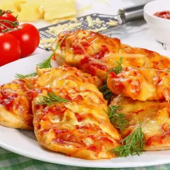 Piersi kurczaka zapieczone z serem i pomidorami, udekorowane koperkiem.