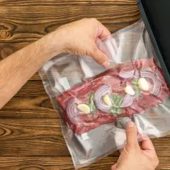 Ręce przygotowują mięso z cebulą i czosnkiem do pakowania próżniowego. Poznaj najlepsze metody na pakowanie próżniowe mięsa bez zepsucia w zamrażarce.