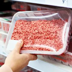 Ręka wybiera mięso mielone z supermarketu, skłaniając do analizy ukrytych konserwantów i soli.