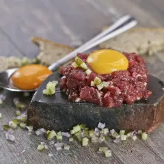 Tatarski stek z surowego mięsa wołowego, jajko i pieczywo. Czy jedzenie surowego mięsa wołowego grozi zakażeniem pasożytami?