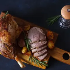 Pieczona jagnięcina z ziemniakami i rozmarynem na desce.
