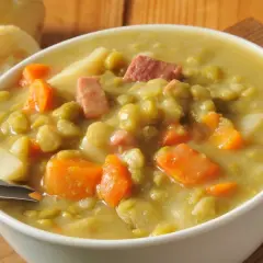 Miseczka grochówki z kawałkami mięsa, marchewki i ziemniaków.