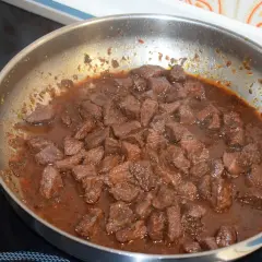 Kawałki wieprzowiny duszą się w sosie, co jest kluczowe, jak zmiękczyć twarde mięso wieprzowe na gulasz naturalnymi metodami.