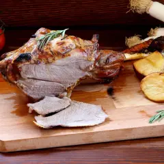 Pieczona jagnięcina z ziemniakami i rozmarynem na desce.