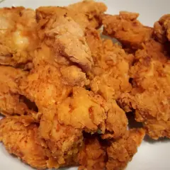 Chrupiące stripsy z kurczaka z airfryera bez kropli oleju, jak z KFC. Złociste i apetyczne kawałki kurczaka na talerzu.