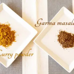 Na talerzykach: żółte curry powder i ciemniejsze garam masala. Poznaj różnice między tymi indyjskimi mieszankami przypraw.