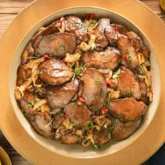 Smażona wątróbka z cebulą i papryczką chili na talerzu.
