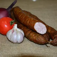 Kiełbasa, cebula, pomidor i czosnek na płóciennym tle.