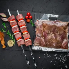 Szaszłyki z wołowiny i warzyw obok próżniowo zapakowanego mięsa. Dowiedz się, jak zapakować próżniowo wołowinę w domu bez specjalistycznej pakowarki.
