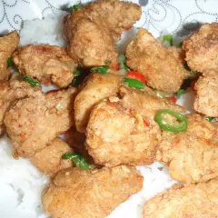 Chrupiący kurczak po koreańsku yangnyeom z podwójnie smażoną panierką ze skrobi, podany na ryżu z papryczkami chili.