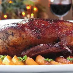 Pieczona kaczka z chrupiącą skórką, podana z jabłkami i ziołami.