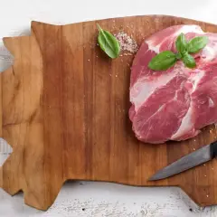 Surowa wieprzowina na desce w kształcie świni. Czy wirus Aujeszkyego w surowej wieprzowinie ginie po ugotowaniu?