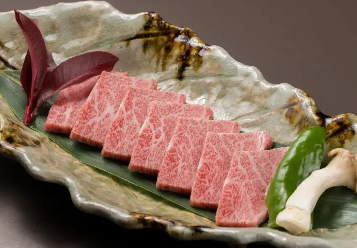 Wołowina wagyu a kobe: czym dokładnie różnią się te gatunki? Delikatne plastry marmurkowego mięsa na liściu, z pieprzem i grzybami.