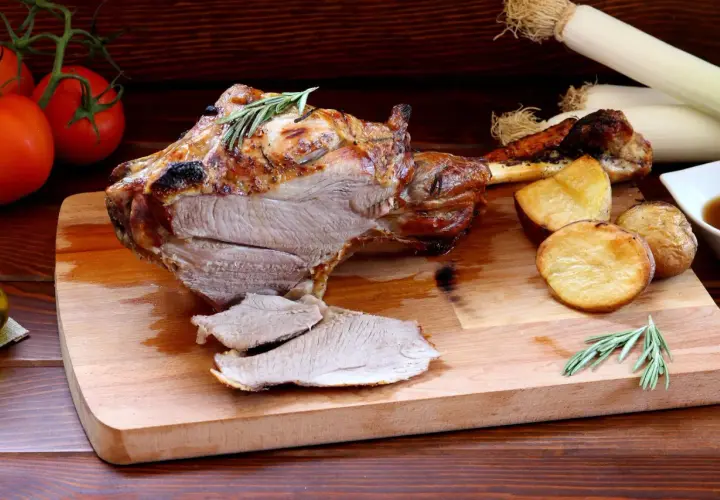 Pieczona jagnięcina z ziemniakami i rozmarynem na desce.