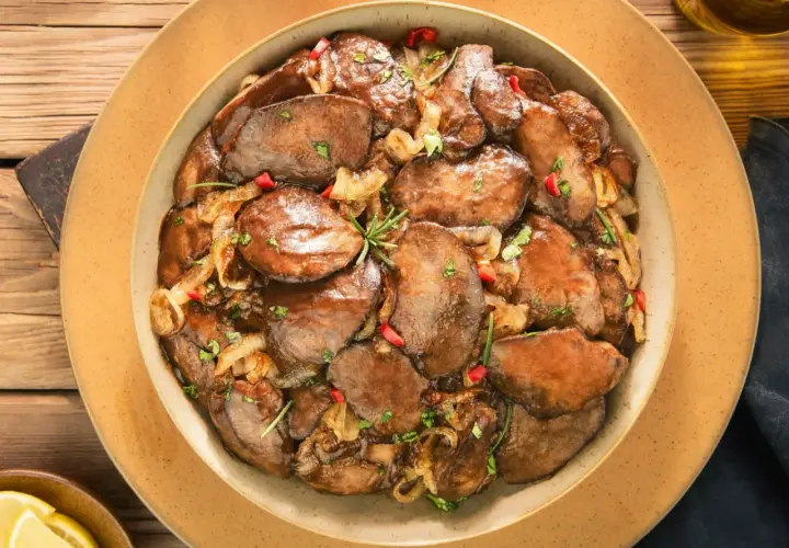 Smażona wątróbka z cebulą i papryczką chili na talerzu.