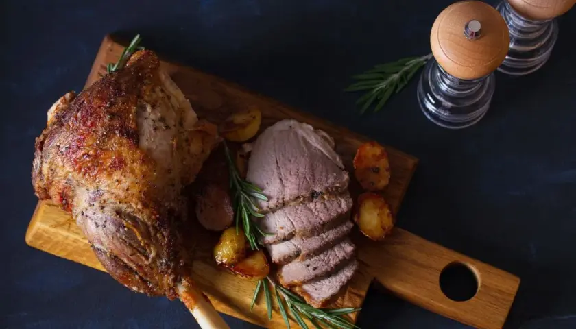 Pieczona jagnięcina z ziemniakami i rozmarynem na desce.