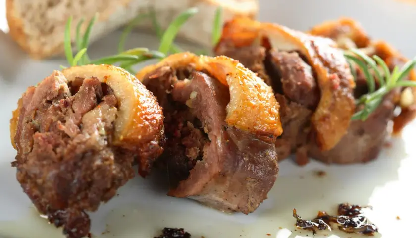 Faszerowana szyja gęsia, tradycyjny przepis babci na zapomniany rarytas z drobiu. Aromatyczne mięso z chrupiącą skórką, podane z pieczywem i rozmarynem.