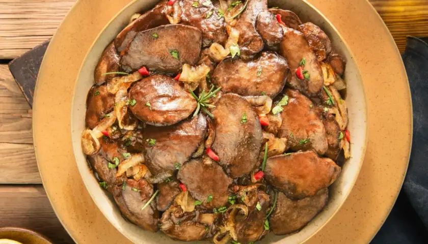 Smażona wątróbka z cebulą i papryczką chili na talerzu.