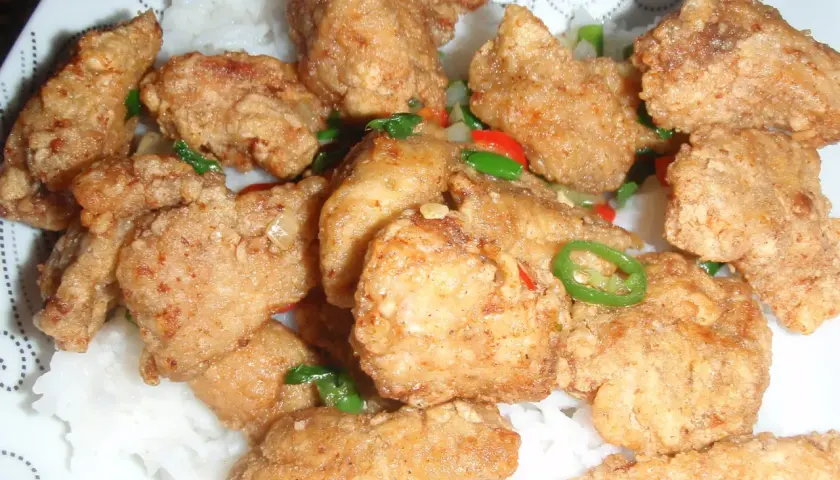 Chrupiący kurczak po koreańsku yangnyeom z podwójnie smażoną panierką ze skrobi, podany na ryżu z papryczkami chili.