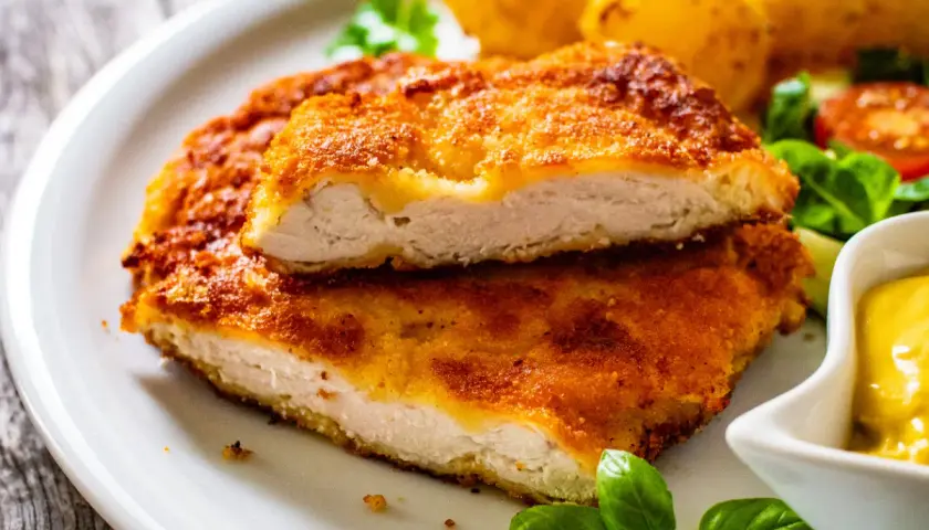 Chrupiący kotlet drobiowy, idealny sposób na to, jak odgrzać smażonego kotleta drobiowego żeby panierka znowu była chrupiąca. Podany z ziemniakami i sosem.