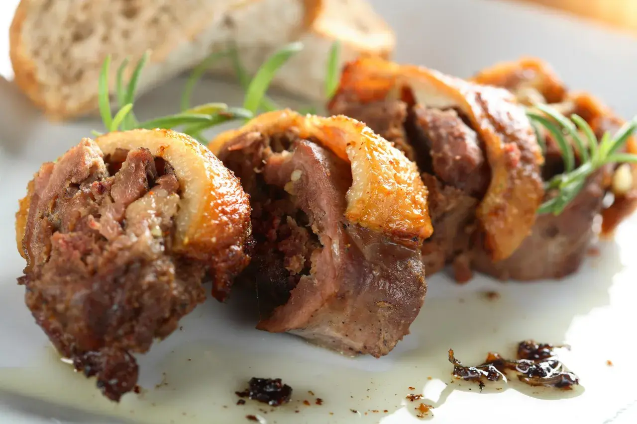 Faszerowana szyja gęsia, tradycyjny przepis babci na zapomniany rarytas z drobiu. Aromatyczne mięso z chrupiącą skórką, podane z pieczywem i rozmarynem.