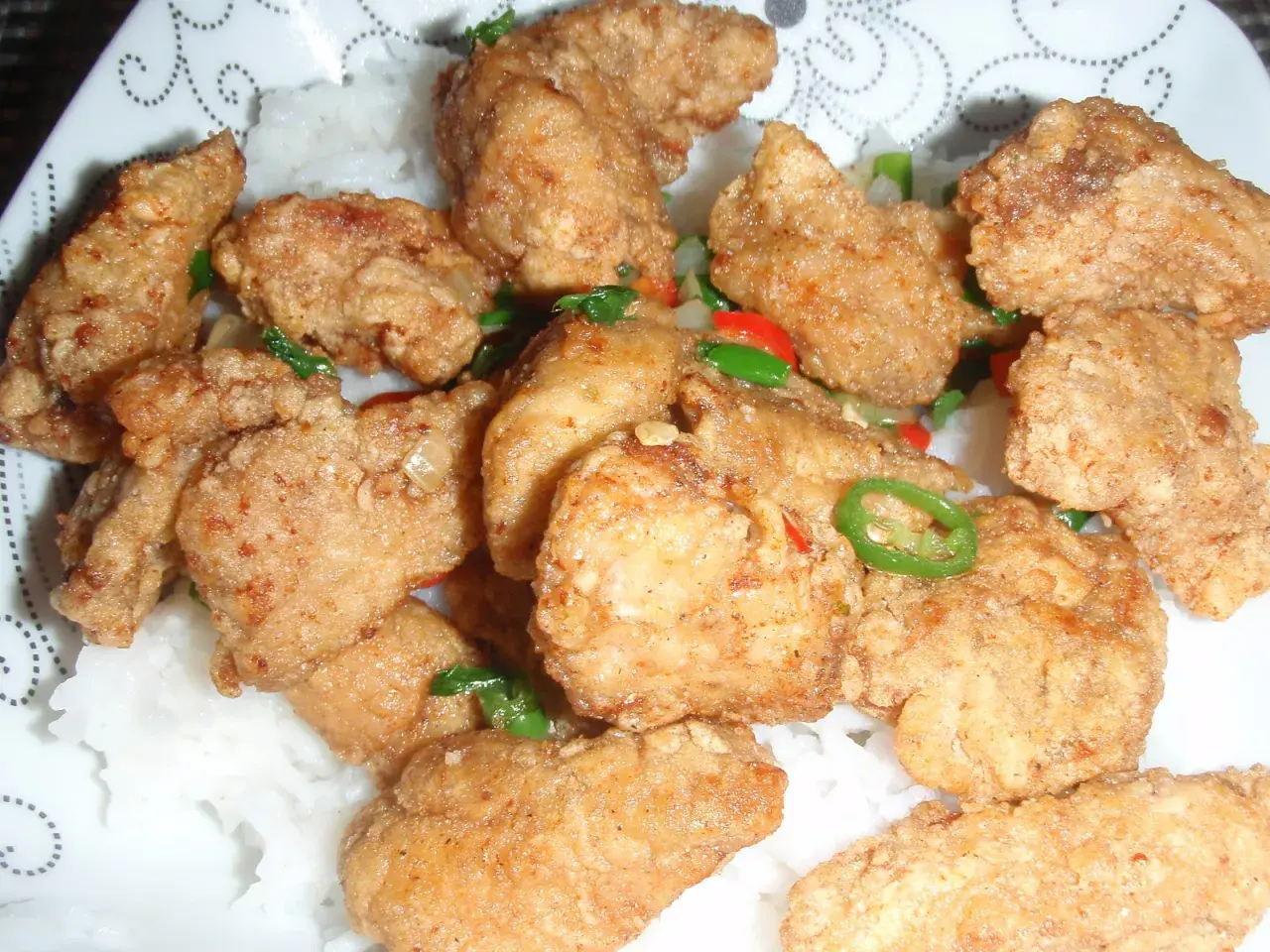 Chrupiący kurczak po koreańsku yangnyeom z podwójnie smażoną panierką ze skrobi, podany na ryżu z papryczkami chili.