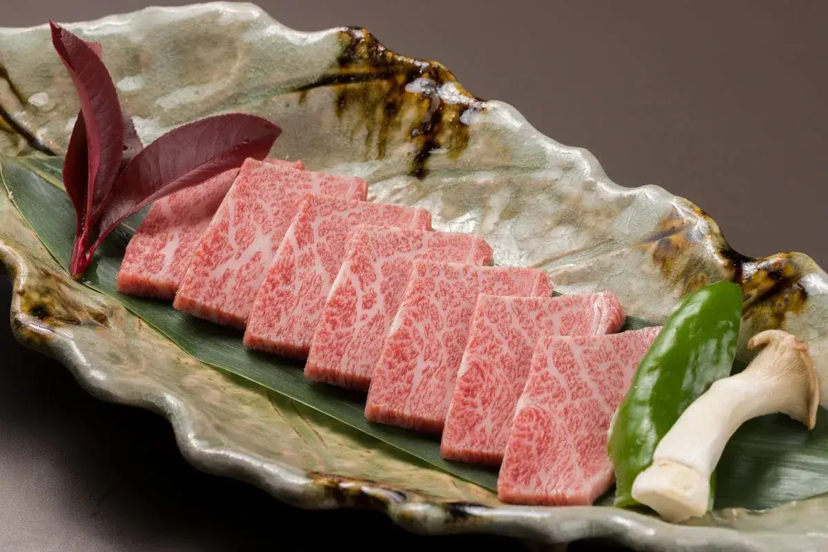 Wołowina wagyu a kobe: czym dokładnie różnią się te gatunki? Pięknie marmurkowate plastry surowej wołowiny na liściu.