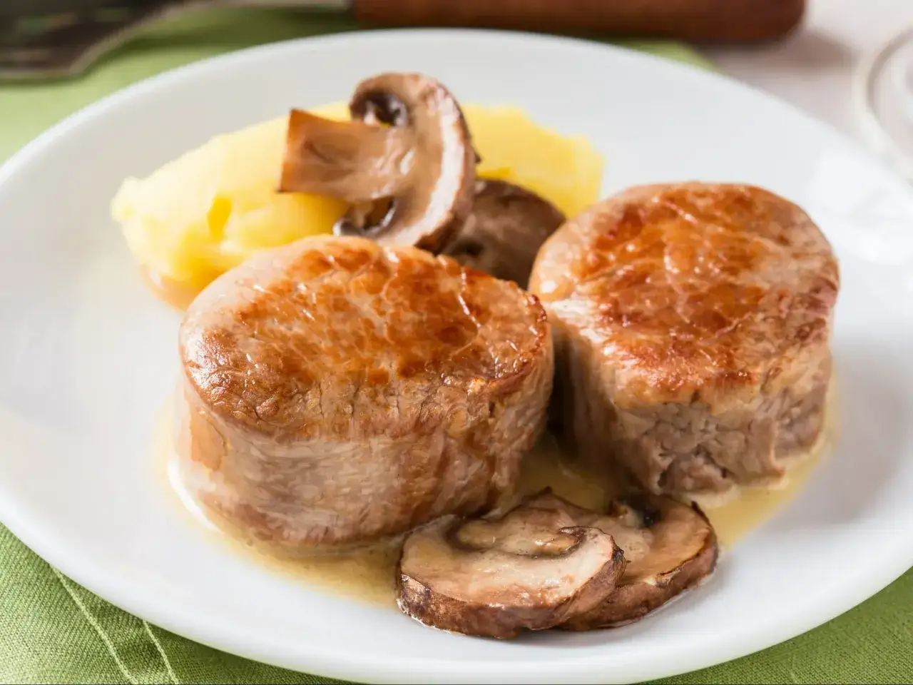 Dwa medaliony z polędwiczki wieprzowej z puree ziemniaczanym i pieczarkami. Prosty trik rzeźnicki, jak wyciąć błonę z polędwiczki wieprzowej, by była soczysta.