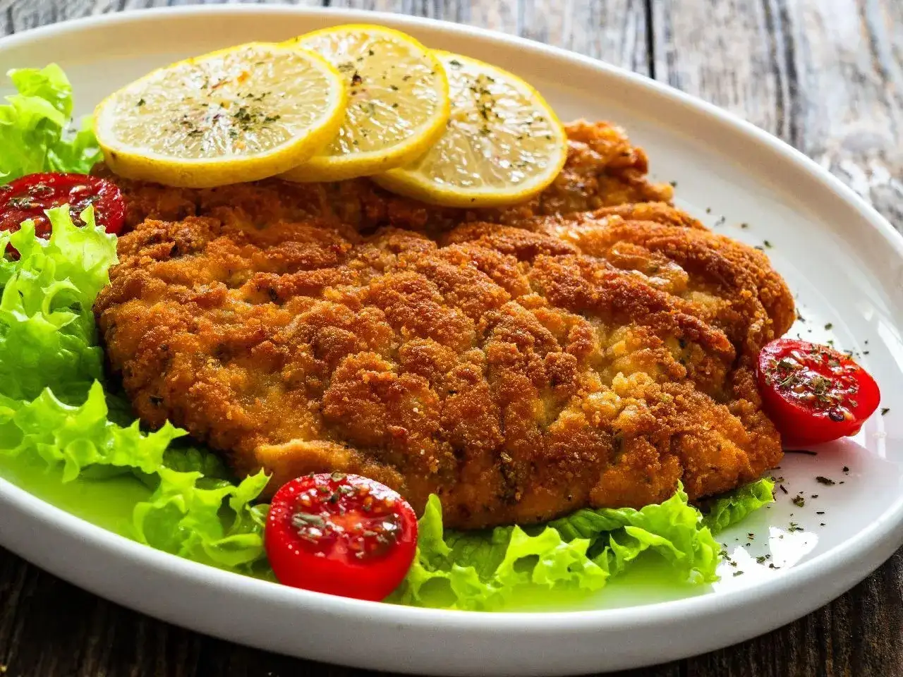 Chrupiący kotlet drobiowy z cytryną i pomidorkami. Dowiedz się, jak odgrzać smażonego kotleta drobiowego, żeby panierka znowu była chrupiąca.