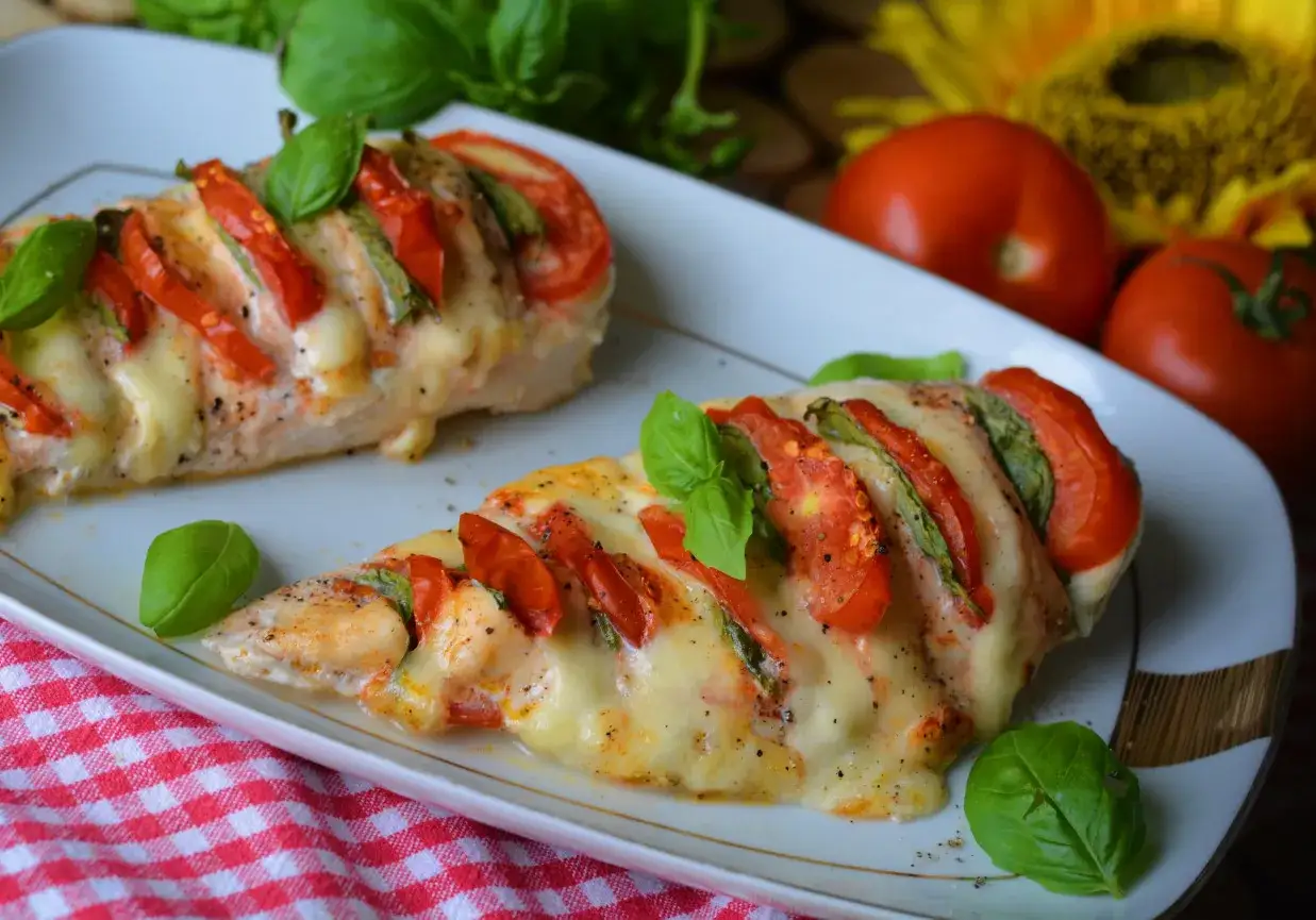 Kurczak caprese z mozzarellą i pomidorami – ekspresowe danie z jednej patelni, ozdobione świeżą bazylią.