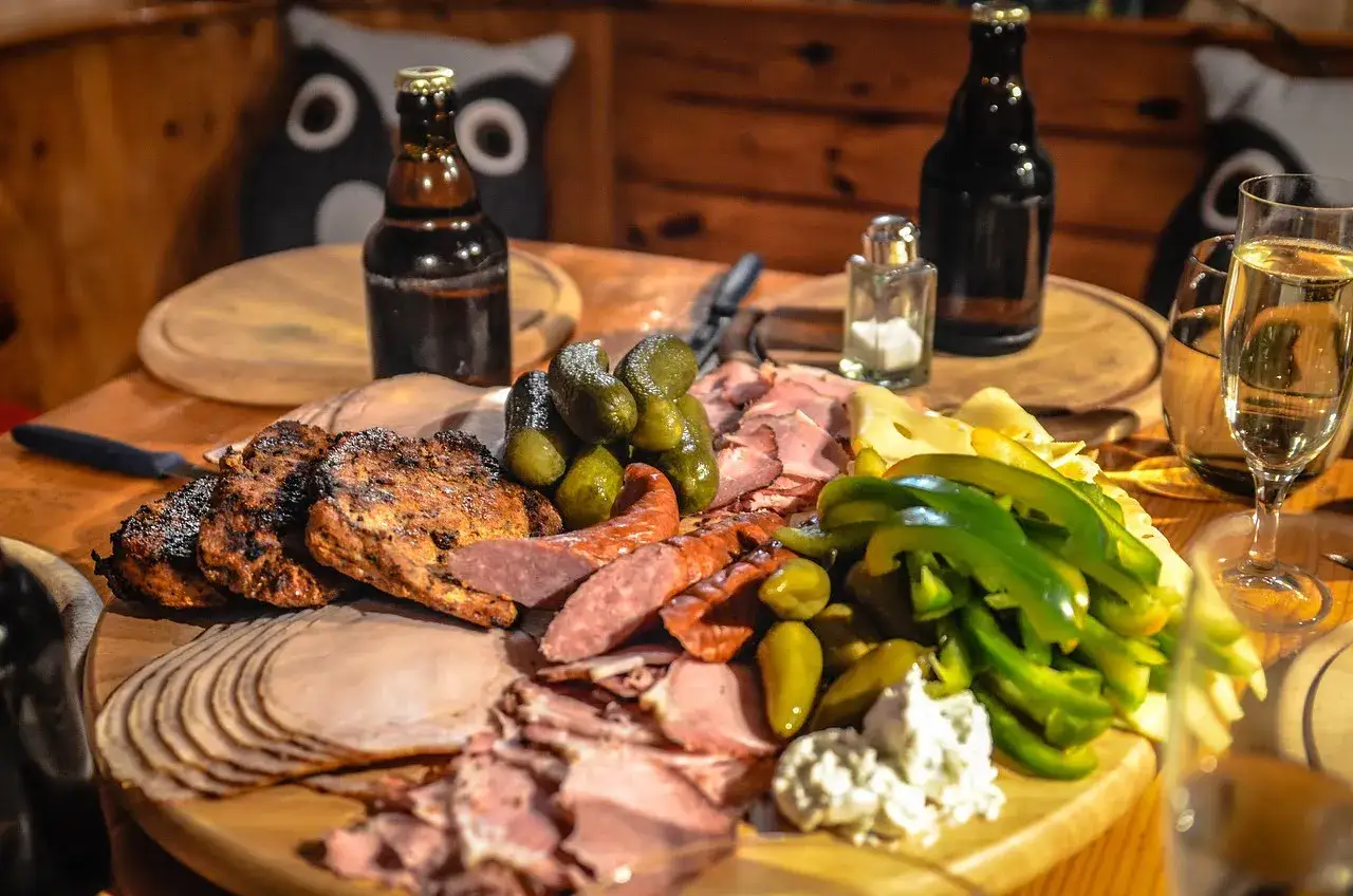 Myśliwi wiedzą, jak pozbyć się zapachu dziczyzny przed gotowaniem. Na stole grillowane mięsa, wędliny, ogórki, papryka i piwo.