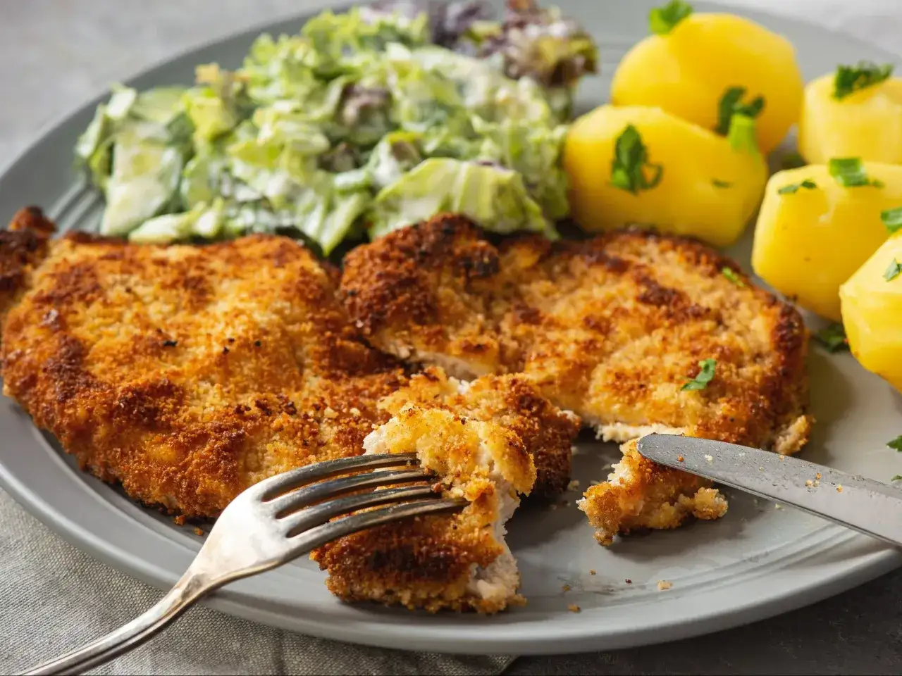 Kotlet schabowy w panierce z ziemniakami i surówką. Szukasz, czym zastąpić jajko w panierce do mięsa w przypadku silnej alergii?
