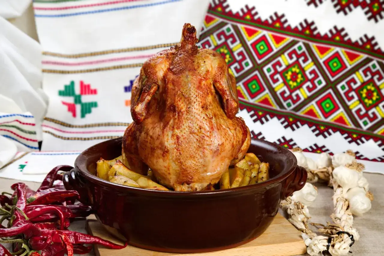 Pieczony kurczak na ziemniakach, otoczony papryczkami chili i czosnkiem. Czy kurczak pieczony na butelce z piwem faktycznie działa na soczystość?