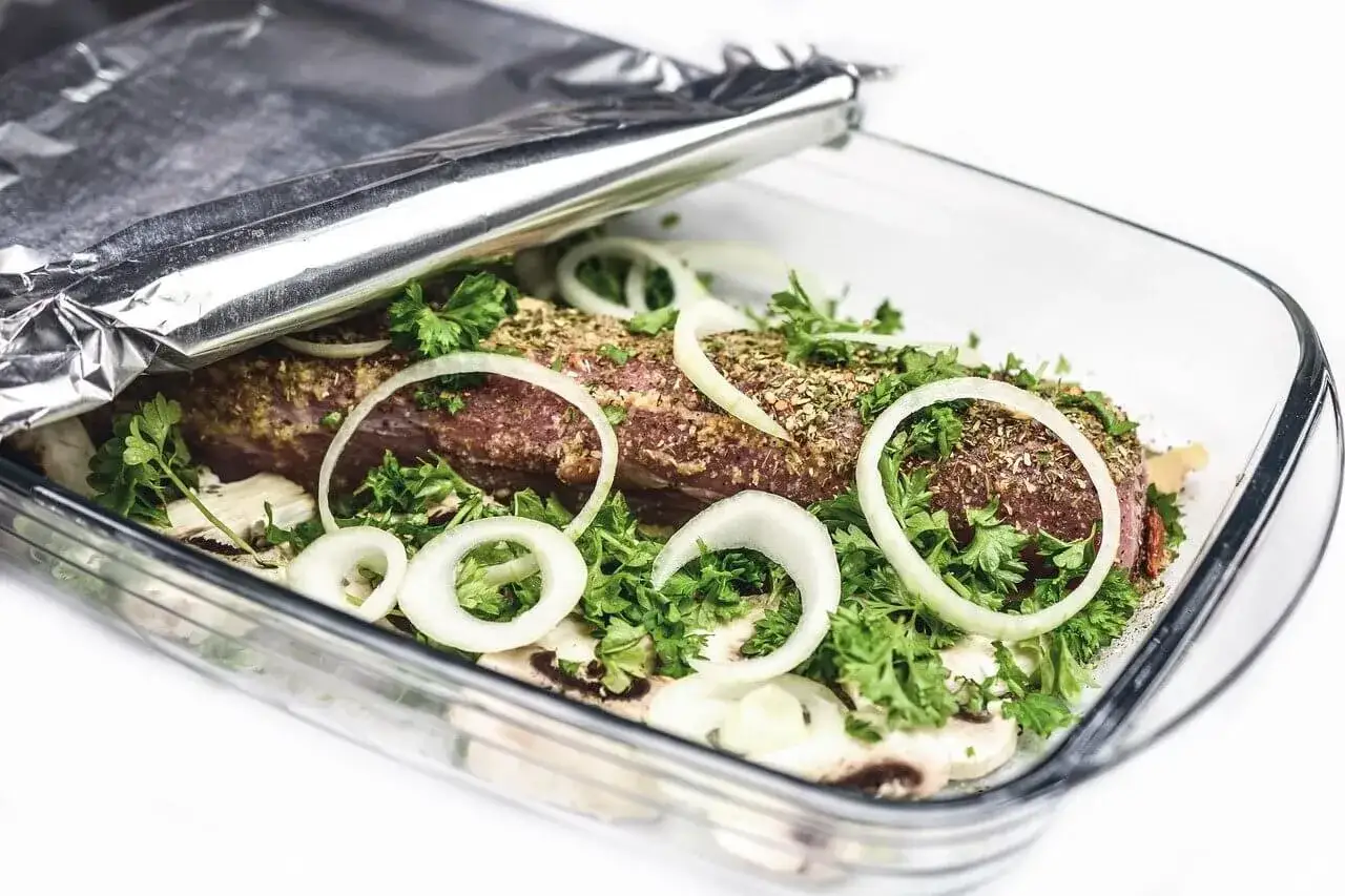 Mięso w naczyniu żaroodpornym, przykryte folią aluminiową. Cebula, pietruszka i pieczarki otaczają pieczeń. Czy błyszcząca strona folii ma znaczenie przy pieczeniu mięsa?