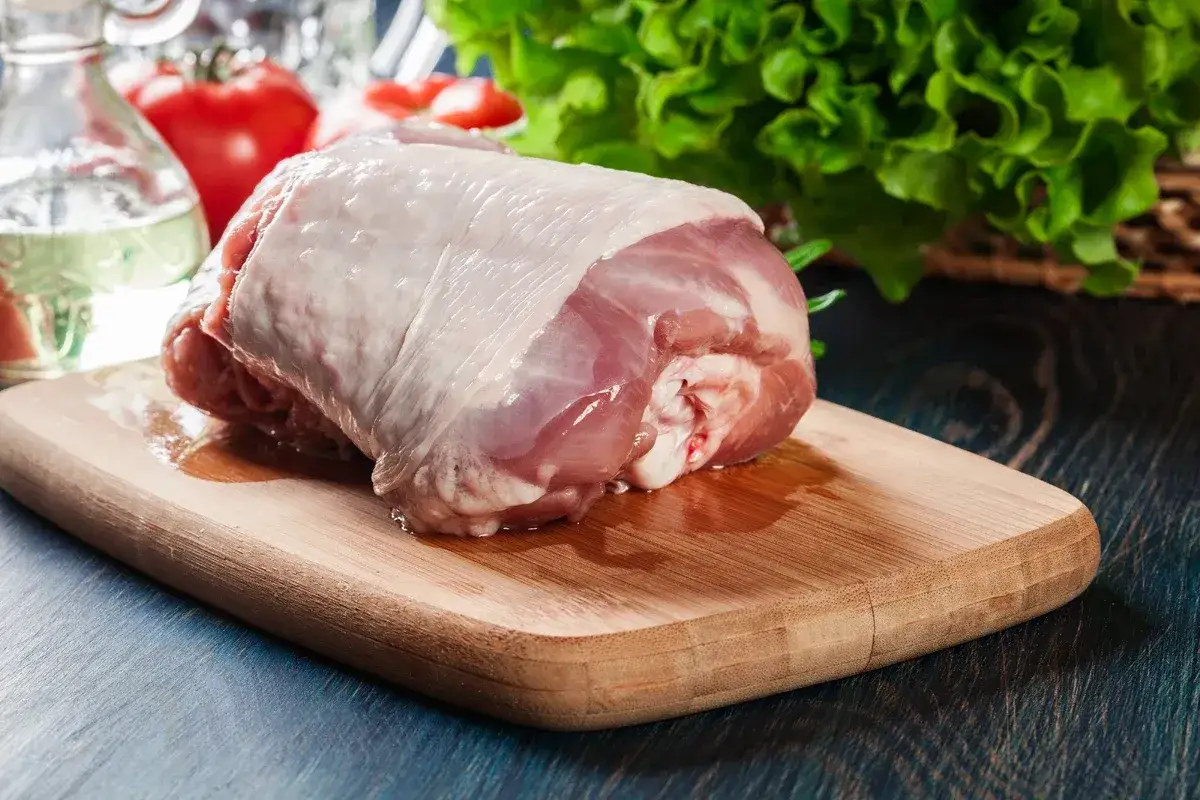 Surowe mięso wieprzowe na desce, przygotowane do smażenia. Dowiedz się, jak zneutralizować zapach starego knura w mięsie wieprzowym przed smażeniem.