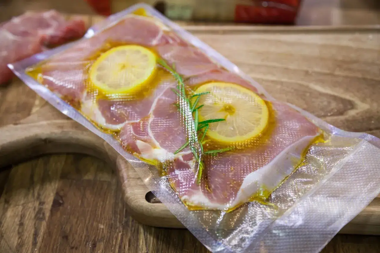 Karkówka wieprzowa w woreczku do metody sous vide, z plasterkami cytryny i rozmarynem. Idealna temperatura dla karkówki w sous vide to klucz do soczystości.