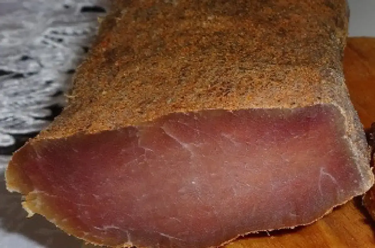 Domowy peklowany schab w pończosze, jak zrobić bezpiecznie bez pleśni. Pokrojony kawałek schabu z przyprawami.