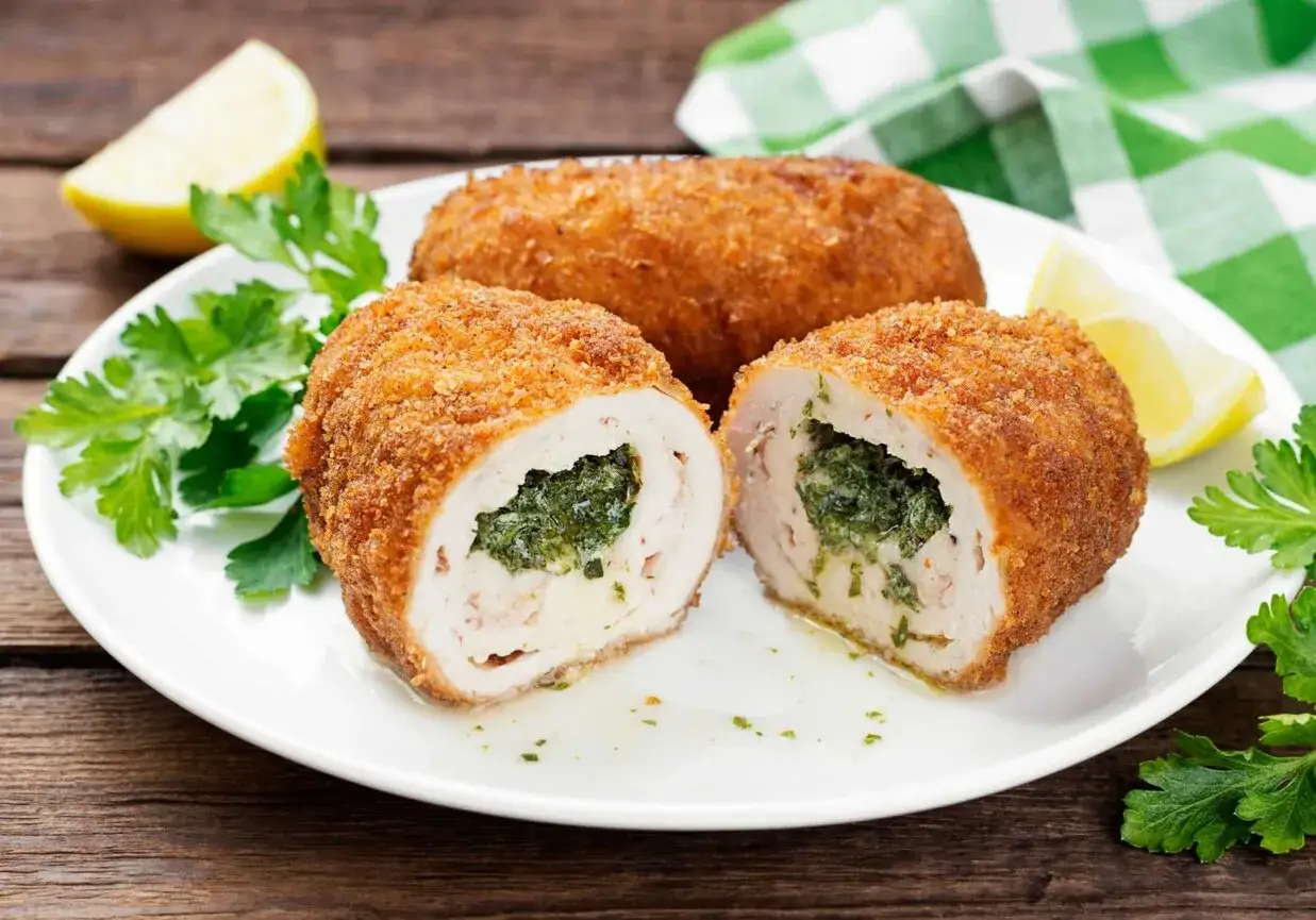 Jak zrobić prawdziwego de volaillea, by masło nie wypłynęło: soczysty kotlet z kurczaka, panierowany, z zielonym nadzieniem i cytryną.
