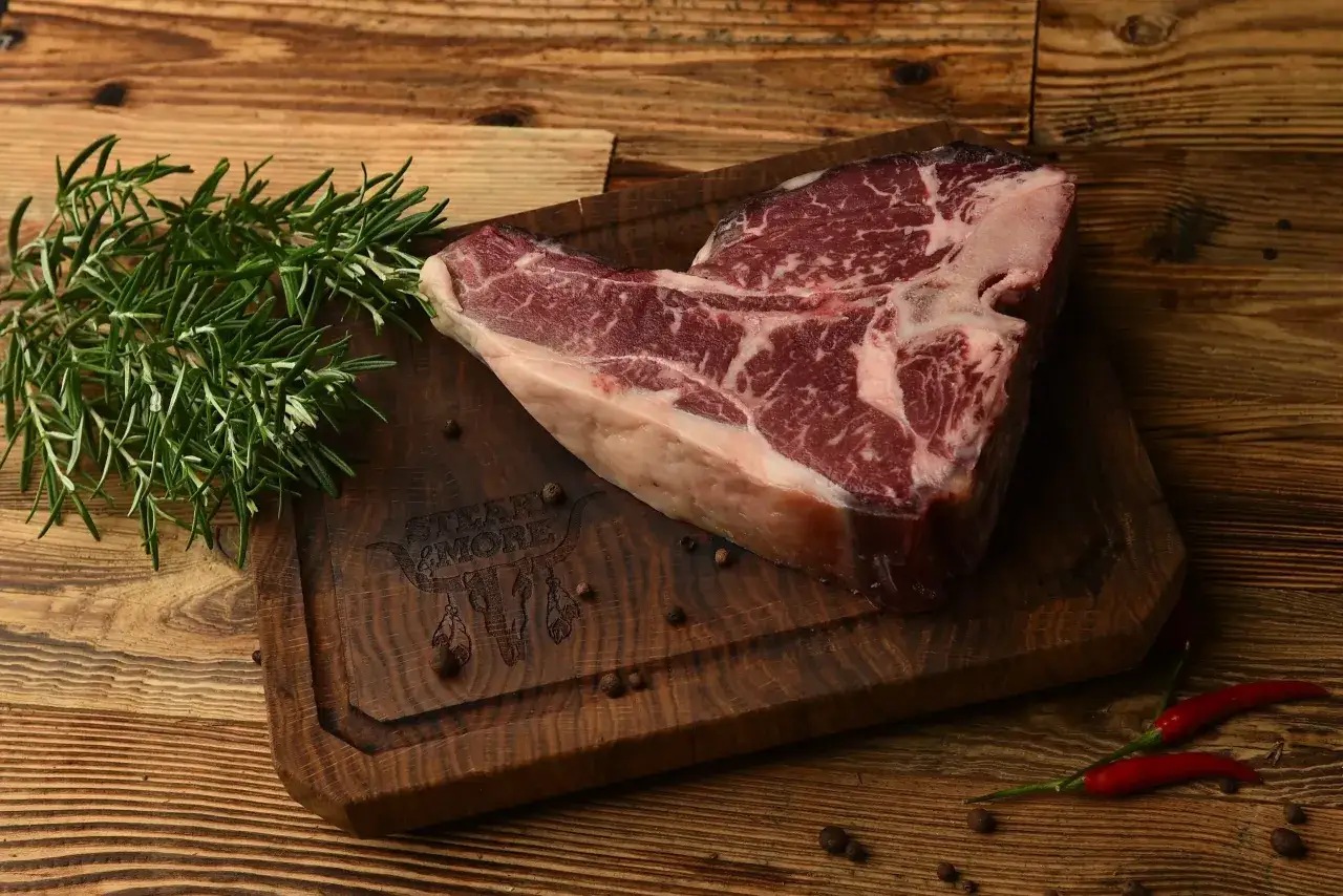 Surowy stek na desce z rozmarynem i pieprzem. Sezonowanie wołowiny na mokro vs na sucho kluczowe różnice w smaku.