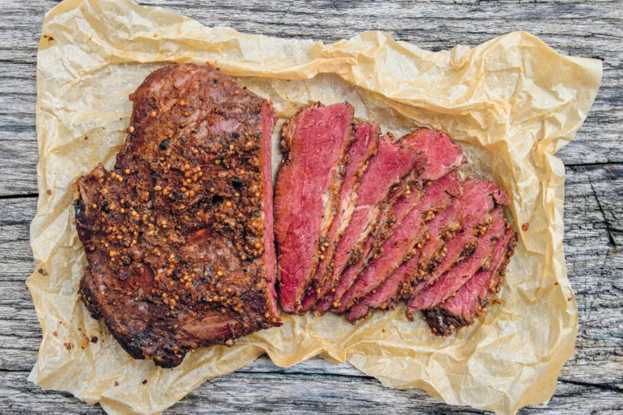 Jak przygotować pastrami z mostka wołowego we własnym domu? Aromatyczny, przyprawiony mostek wołowy, pokrojony w plastry, na papierze do pieczenia.