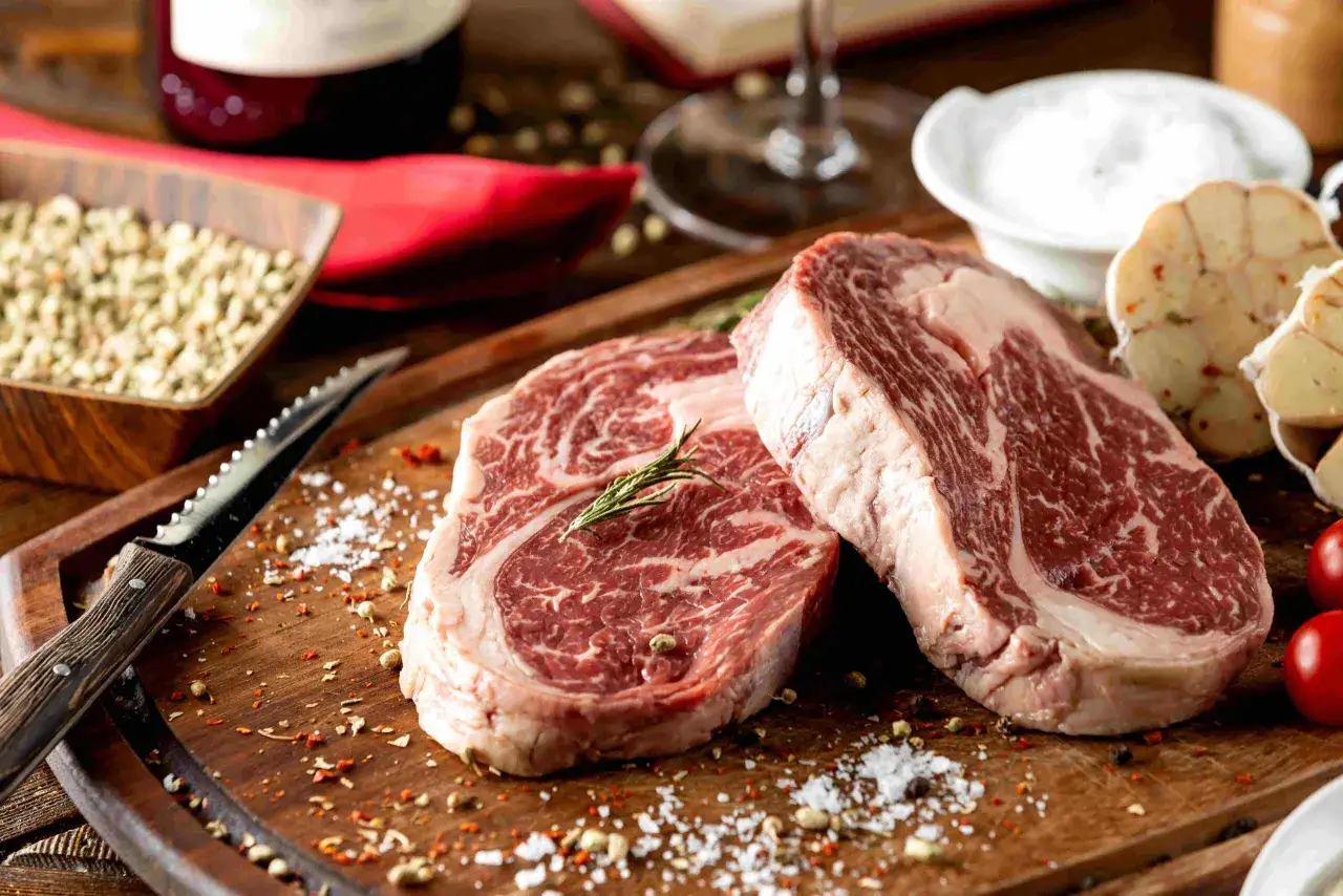 Dwa soczyste steki wołowiny wagyu a kobe czym dokładnie różnią się te gatunki, przyprawione solą i pieprzem, na drewnianej desce.