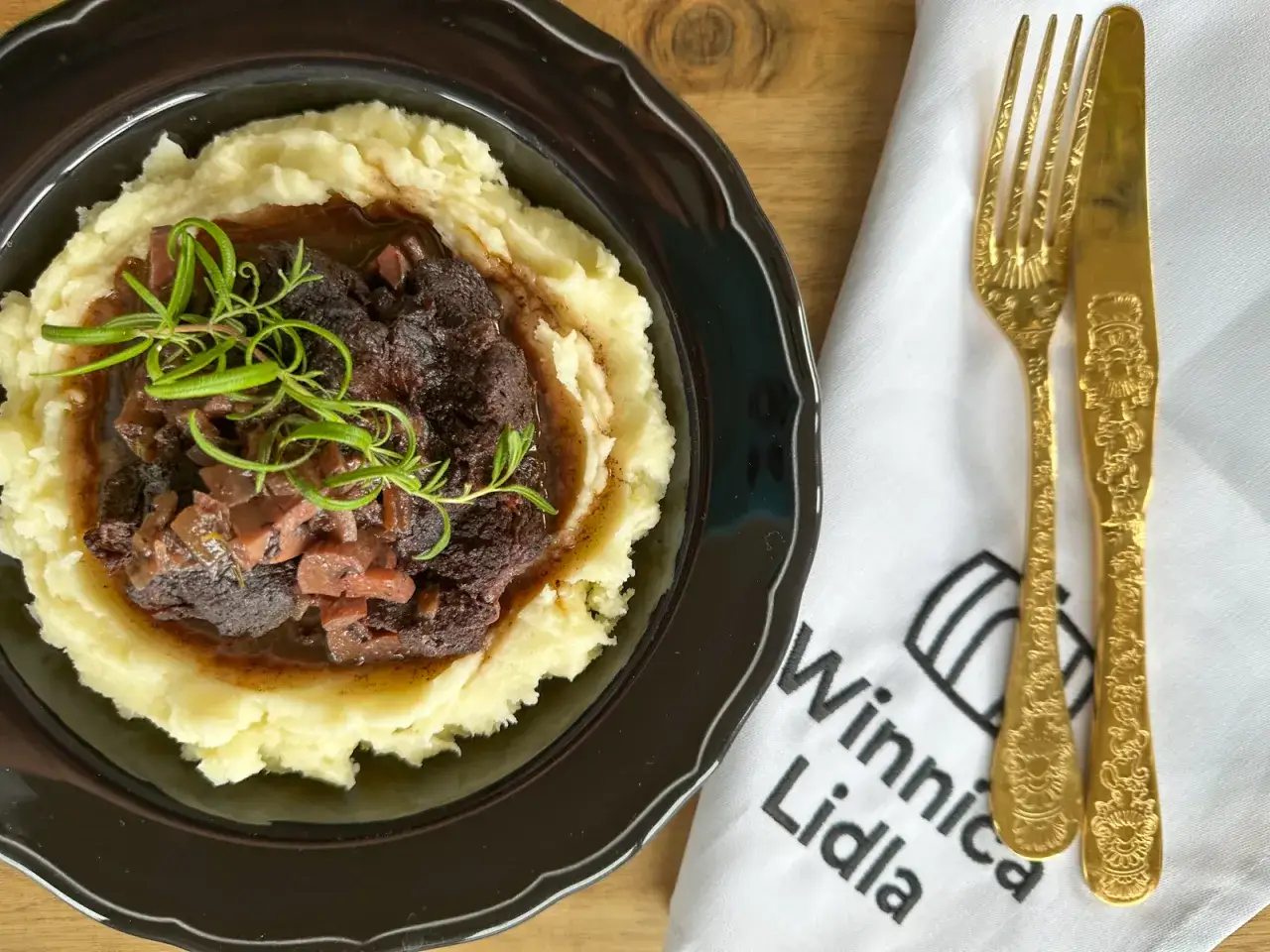 Wołowina po burgundzku, podana na kremowym purée ziemniaczanym, z gałązką rozmarynu. To autentyczny i tradycyjny przepis na to danie.