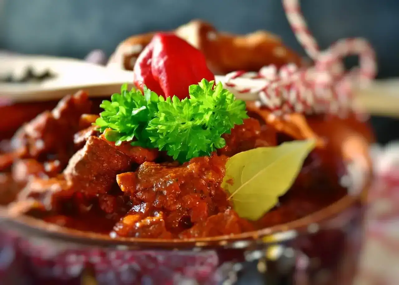 Gulasz z indyka, jak uratować przesolony? Szybkie sposoby na neutralizację smaku. Aromatyczne danie z indyka, ozdobione natką pietruszki i papryczką.